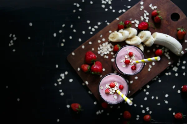 Erdbeer-Bananen-Smoothie im Glas auf schwarzem Hintergrund — Stockfoto