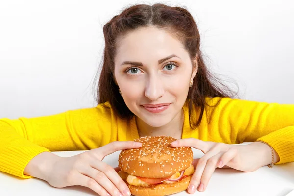 Meisje bijt uit een grote hamburger. Ongezonde voeding. — Stockfoto