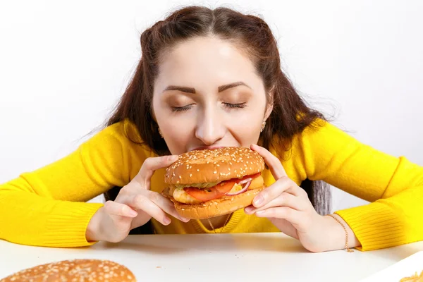Κορίτσι δαγκώνει μακριά ένα τεράστιο χάμπουργκερ. Ανθυγιεινή διατροφή. — Φωτογραφία Αρχείου