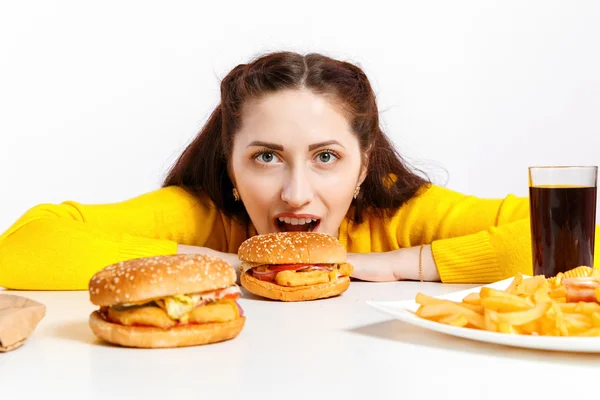 女の子は、巨大なハンバーガーをかみます。不健康な食事. — ストック写真