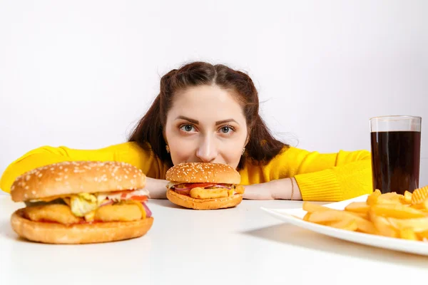 Meisje bijt uit een grote hamburger. Ongezonde voeding. — Stockfoto