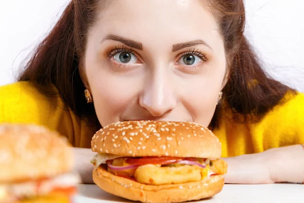 Meisje bijt uit een grote hamburger. Ongezonde voeding. — Stockfoto