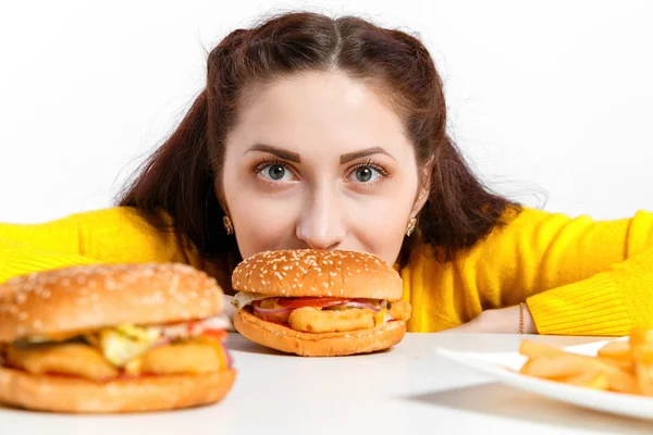 A rapariga morde um hambúrguer enorme. Dietas pouco saudáveis . — Fotografia de Stock