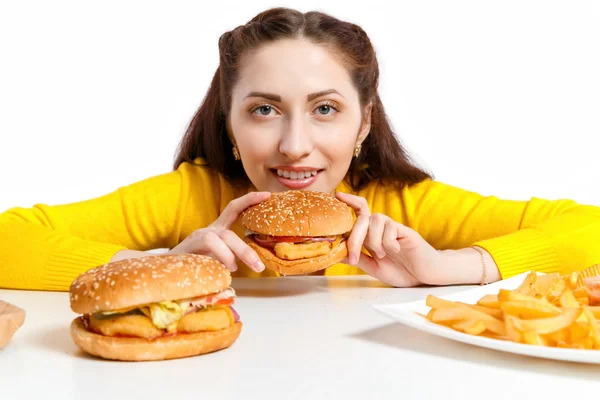 女の子は、巨大なハンバーガーをかみます。不健康な食事. — ストック写真