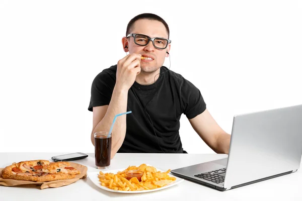 Um homem a trabalhar no computador e a comer fast food. Vida não saudável — Fotografia de Stock