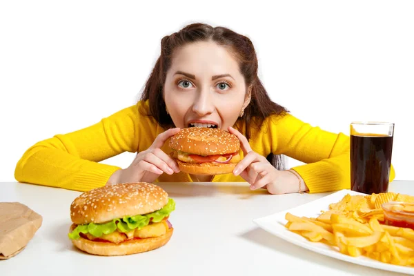 Girl bites off a huge hamburger. — Stock Photo, Image