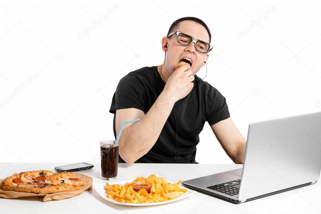 Man working at the computer and eating fast food. Unhealthy Life
