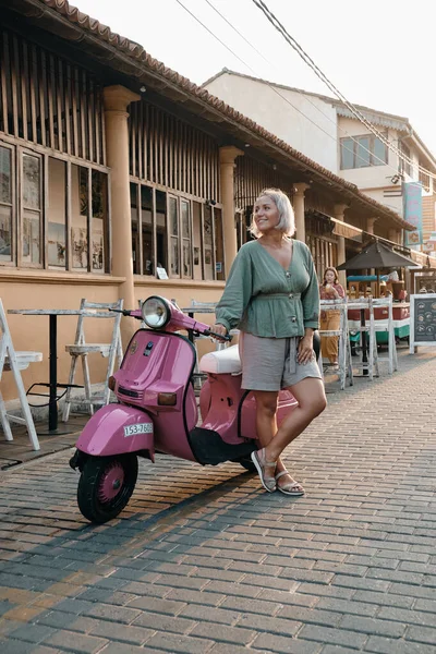 Sorrindo feliz mulher sentada em moto roxa — Fotografia de Stock