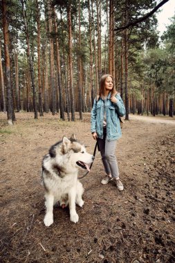 Genç kız ve köpeği Alaska Malamute, Sonbaharda açık havada. Evcil hayvan