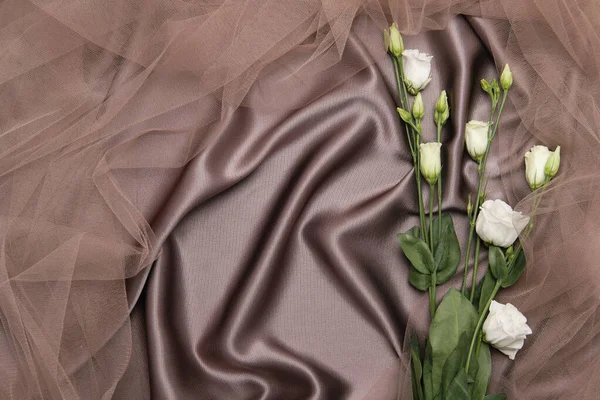 Bouquet di rose bianche su uno sfondo di seta marrone e tulle. Sfondo da tessuto con fiori. — Foto Stock