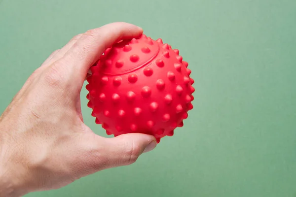 Egy férfi kezében egy labda a ravaszpontok kidolgozásához, vagy egy fizikoterápiás labda a reflexológiához. Fizioterápiás fogalom. — Stock Fotó