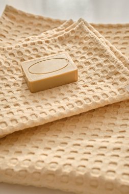 El yapımı doğal zeytin sabunu doğal bir muslin havlusunun üzerinde yatar. Bej renginde kompozisyon.