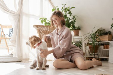 Sabahları pijamalı, evde köpeğiyle gülümseyen tatlı bir kız..