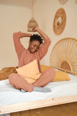 Yatak odasında dizüstü bilgisayar kullanarak yatakta oturan mutlu genç kız. Muslin pijaması. Arkadaşlarla sohbet. 