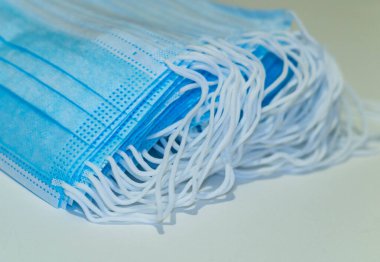 Tek kullanımlık tıbbi maske. Mavi koruyucu maske beyaz arka planda izole edilmiş. Birçok tıbbi maske kapanır. Koronavirüsten koruyan cerrahi yüz maskesi. İlaç ve sağlık hizmetleri