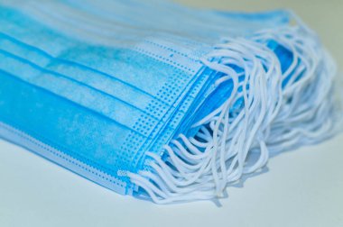 Tek kullanımlık tıbbi maske. Mavi koruyucu maske beyaz arka planda izole edilmiş. Birçok tıbbi maske kapanır. Koronavirüsten koruyan cerrahi yüz maskesi. İlaç ve sağlık hizmetleri