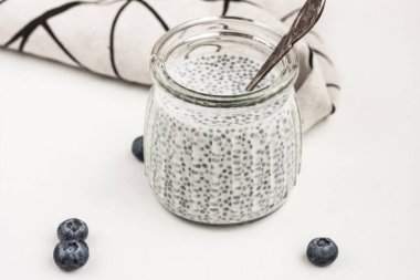 Hindistan cevizi tohumu pudingi beyaz arka planda cam kavanozda. Sağlıklı glütensiz süper yiyecekler konsepti. Üst görünüm, stok fotoğrafı