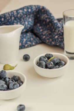Mavi ve beyaz arka planda taze yaban mersini ve süt. Sağlıklı kahvaltı kavramı