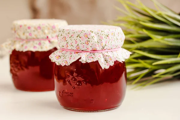 Glass jars of red currant jelly on white table. Preserved berries, homemade jam. Copy space