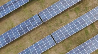 Kuşbakışı yeşil çimenli alanlardaki sıra sıra güneş panellerini gösteren drone videosu