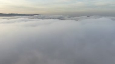 Kameranın beyaz bulutların üzerinden uçuşu. Ufuktaki dağlar resim gibi gökyüzünün arka planına karşı. İHA 4K. Kuş bakışı.