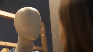 Sırtı dönük duran ve vitrinden manikine bakan bir kızın kafası. Yakın plan.
