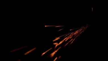 Karanlıkta kırmızı ateş parçacıkları düşüyor.