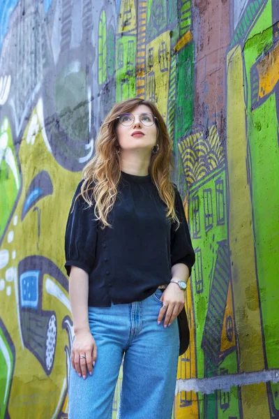 Portrait of a girl on the background of a wall with graffiti