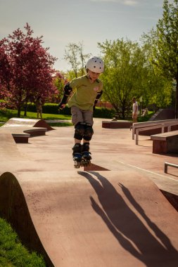 Bir çocuk kaykay parkında paten kayıyor.