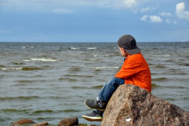 Çocuk denize bakıyor.