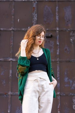 Eski demir bir kapının arkasında yeşil ceketli bir kız.