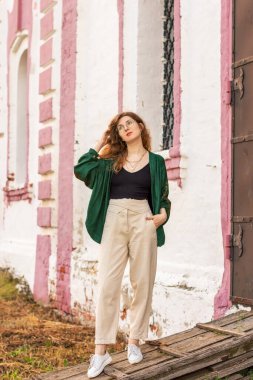 Eski bir binanın arka planında yeşil ceketli bir kız.