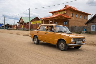 Eski Sovyet retro arabası Sibirya 'nın doğusundaki Baykal Gölü' nün Olkhon Adası 'ndaki Khuzhir köyünde ana cadde boyunca sürüyor. Fotoğraf Temmuz 'da yazın çekildi..