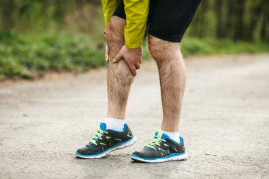 Spor ayakkabılı bir adamın doğada koşarken bacağının yaralandığı görüntüler.