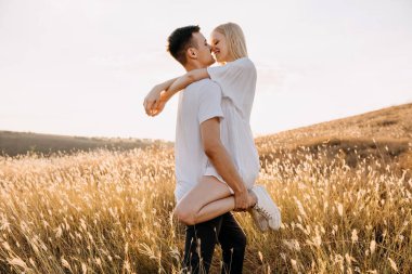 Gün batımında çayırda kucaklaşan güzel genç çift.