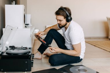 Yakışıklı genç adam evde plak dinliyor.