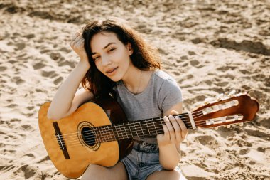 Kumsalda akustik gitarlı güzel genç bir kadın.