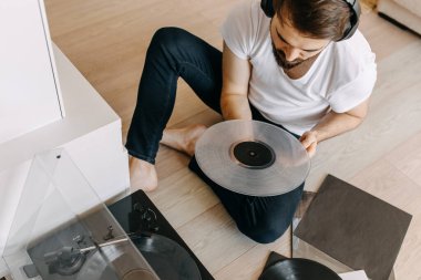 Yakışıklı genç adam evde plak dinliyor.