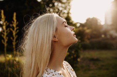 Çiçekli çayırlarda giyinmiş güzel bir genç kadının portresi.