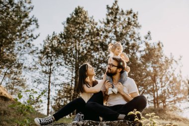 Mutlu genç aile doğada birlikte vakit geçiriyor.