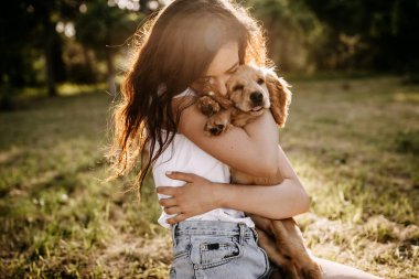 Cocker spaniel köpeğiyle birlikte parkta vakit geçiren güzel genç bir kadın.