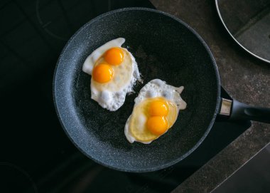 Siyah arka planda tavada yumurta.