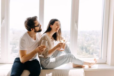 Pencere kenarında oturan ve evde birlikte vakit geçiren genç ve güzel bir çift.