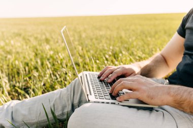 Sahada dizüstü bilgisayar kullanan bir adam görüntüsü.