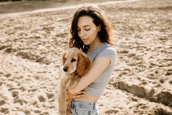 漂亮的年轻女子带着她的小猎犬在海滩上共度时光 — 图库照片