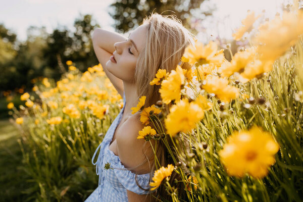 portrait of beautiful young woman in summer dress on green meadow with yellow flowers