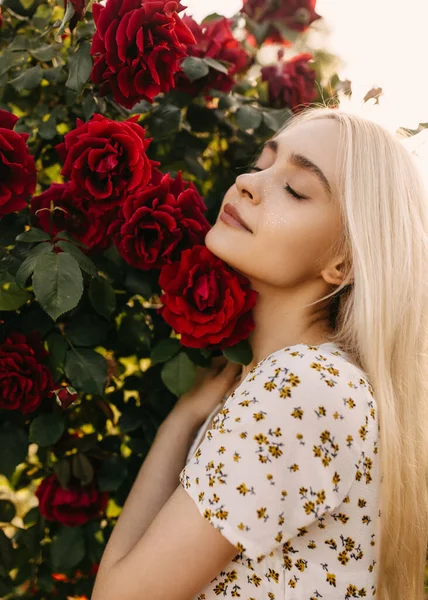 庭のバラの茂みの前で美しい若い女性の肖像画 — ストック写真