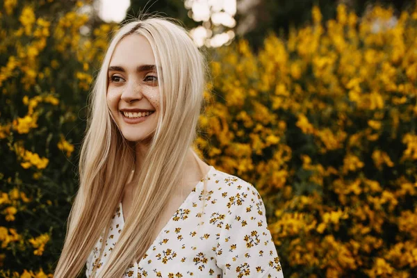 stock image portrait of beautiful young woman in dress in front of yellow flowery bush in garden