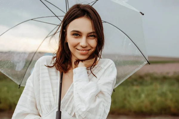 美しい若い女性の肖像画の花の牧草地で透明な傘 — ストック写真