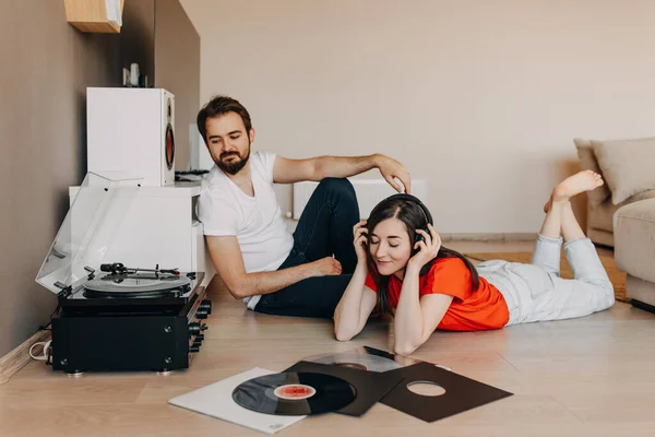 beautiful young couple listening vinyl records together at home